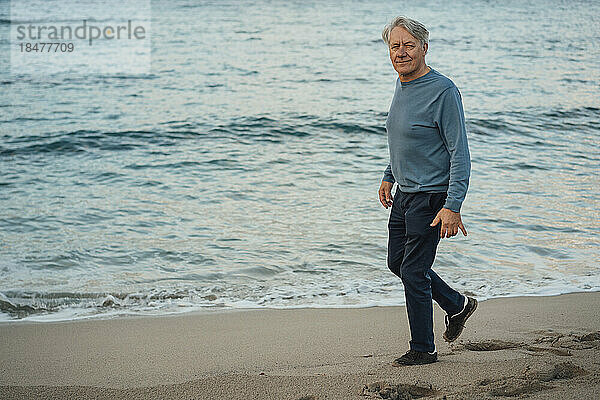 Lächelnder älterer Mann  der am Strand spaziert