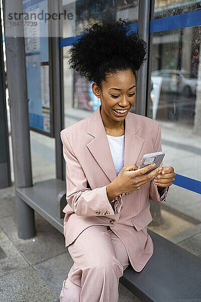 Glückliche Geschäftsfrau benutzt Smartphone auf Bank