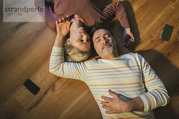 Ehepaar mit geschlossenen Augen ruht zu Hause auf dem Boden