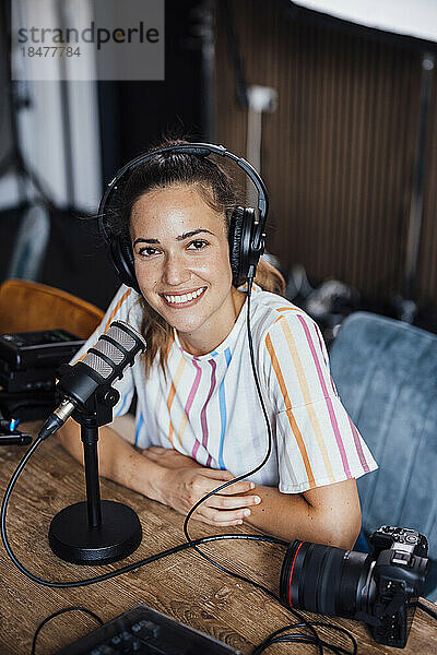 Glücklicher Podcaster  der mit Mikrofon im Studio sitzt