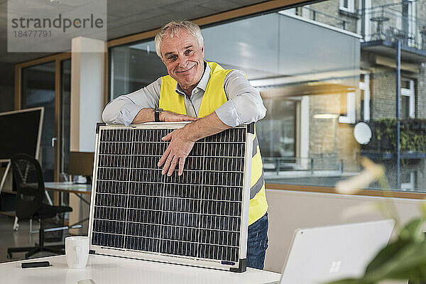 Lächelnder leitender Ingenieur mit Solarpanel im Büro