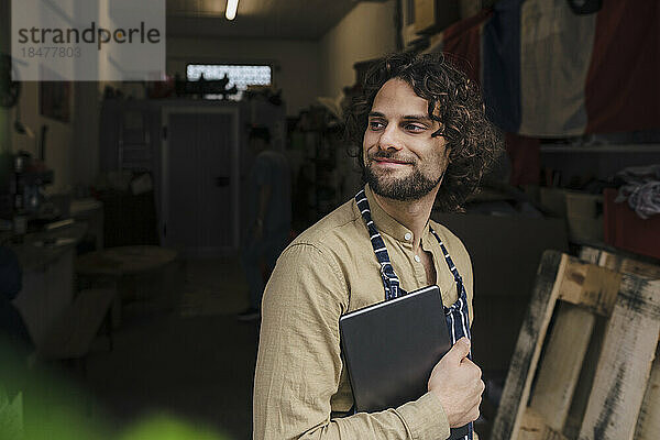 Lächelnder junger Geschäftsmann hält Tablet-Computer im Lagerraum