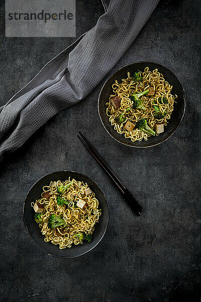 Studio shot of two plates of ready-to-eat vegan noodles with broccoli  tofu and soy sauce