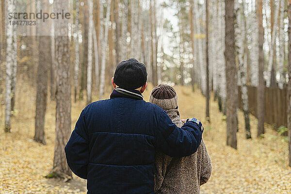 Älterer Mann mit Arm um Frau und Blick auf Bäume im Park