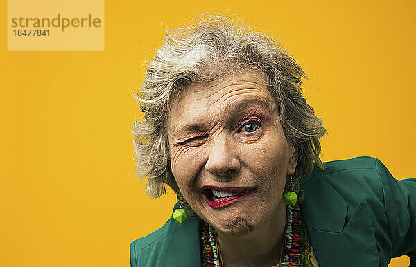 Ältere Frau mit Gesichtsausdruck vor gelbem Hintergrund