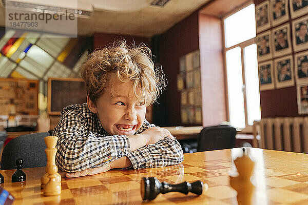 Boy sitting at table playing chess in country club
