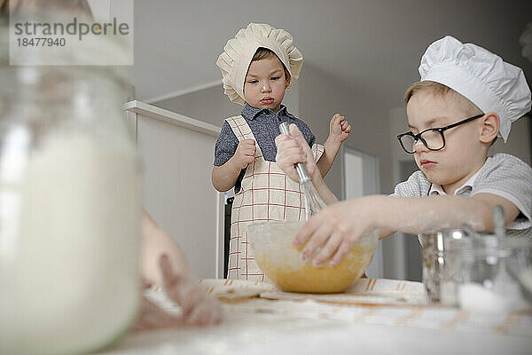 Boy mixing batter with wire whisk in kitchen