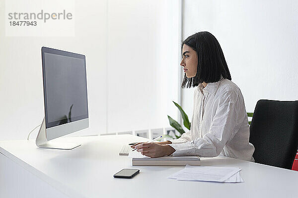 Junge Geschäftsfrau arbeitet am Schreibtisch am Desktop-PC