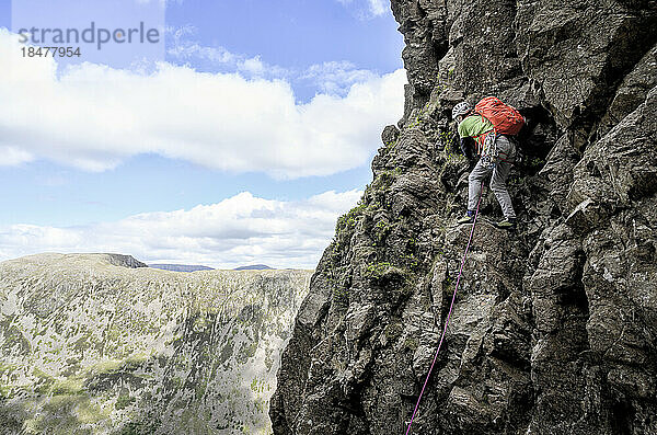 Mann mit Rucksack klettert auf Berg  Lake District  England