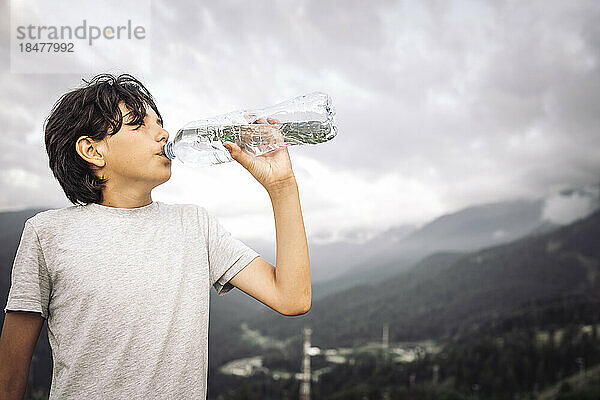 Durstiger Junge trinkt Wasser aus der Flasche