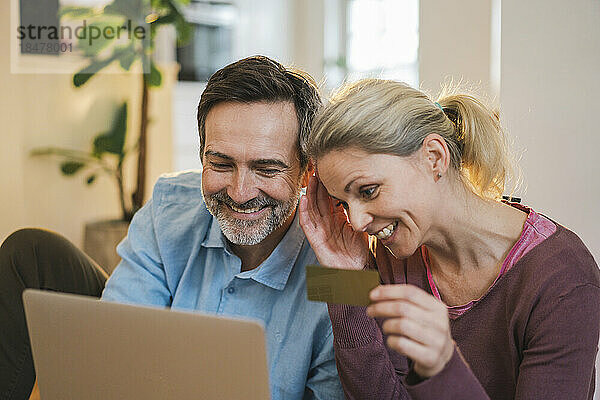 Glückliches Paar beim Online-Shopping per Laptop zu Hause