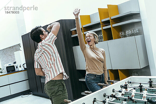 Cheerful businesswoman and businessman playing foosball at office