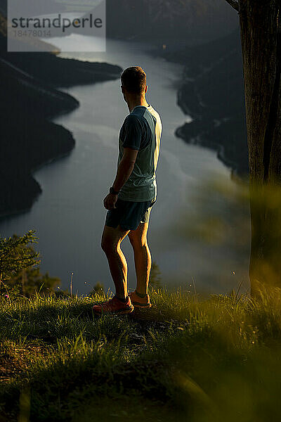 Sportler bewundert den See  der bei Sonnenuntergang auf dem Berg steht