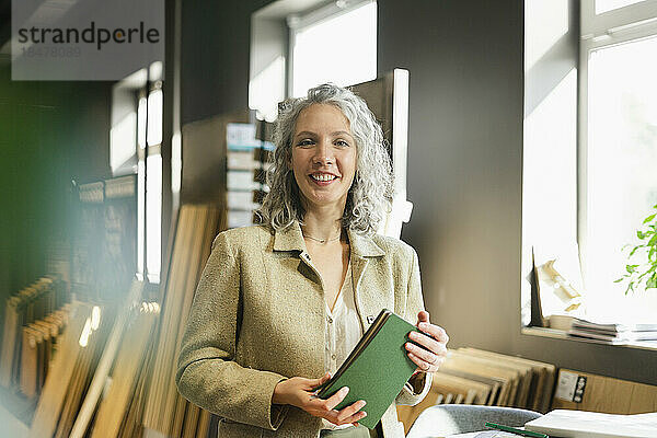 Porträt einer lächelnden Architektin mit Notizbuch im Büro