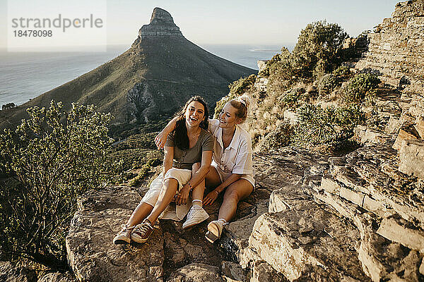 Friends enjoying sunset sitting on rock of Signal Hill