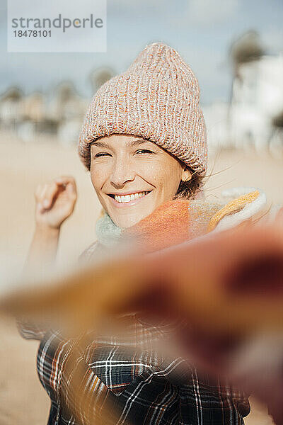 Fröhliche Frau mit Strickmütze am Strand