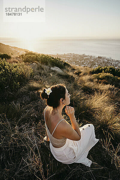 Junge Frau sitzt bei Sonnenuntergang auf dem Signal Hill