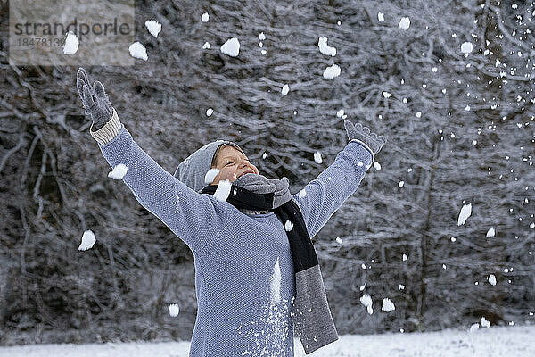 Fröhlicher Junge in warmer Kleidung  der den Schnee genießt