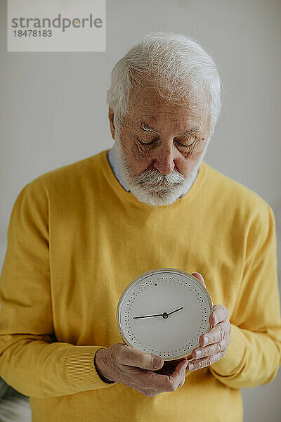 Älterer Mann mit Uhr steht vor der Wand