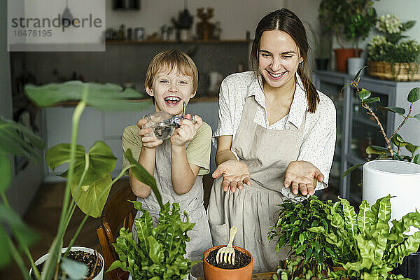 Glückliche Mutter und Sohn kümmern sich zu Hause um Pflanzen