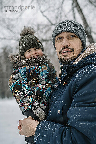 Vater trägt Sohn und hat Spaß im Schnee