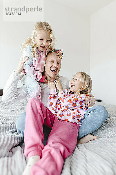 Cheerful father having fun with daughters at home