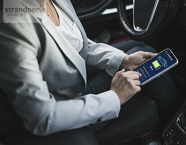 Hände einer Frau untersuchen die Lade-App für Elektroautos auf ihrem Mobiltelefon