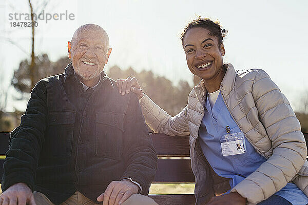 Glücklicher Hausmeister und älterer Mann  der an einem sonnigen Tag im Park sitzt