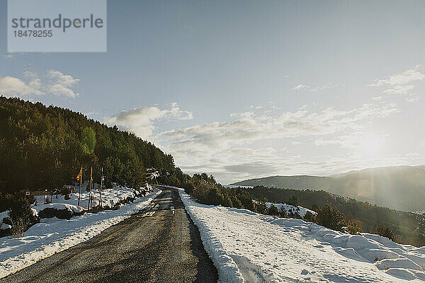 Leere Bergstraße inmitten von Schnee im Winter an sonnigen Tagen