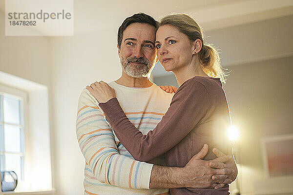 Thoughtful mature couple standing at home