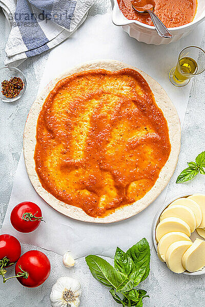 Flay lay of pizza dough with tomato sauce and ingredients kept on table