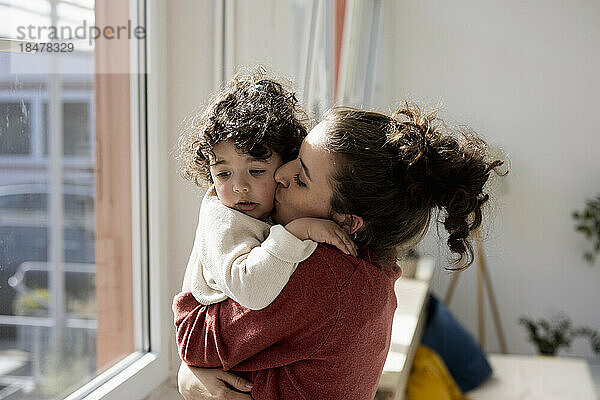 Mother holding and cuddling little daughter at home