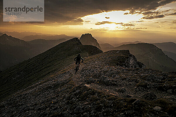 Mann beim Mountainbiken bei Sonnenuntergang