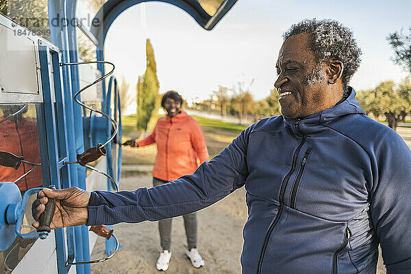 Glücklicher älterer Mann hält Trainingsgeräte im Park