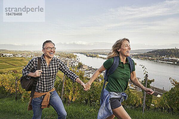 Glückliches Paar hält Händchen und genießt das Wandern auf dem Hügel