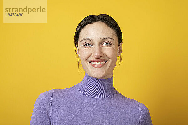 Glückliche Frau mit lila Rollkragenpullover auf gelbem Hintergrund