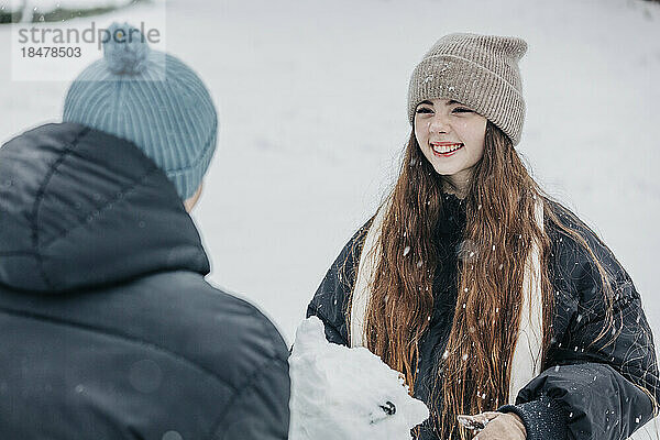 Glückliche Frau schaut ihren Freund im verschneiten Park an
