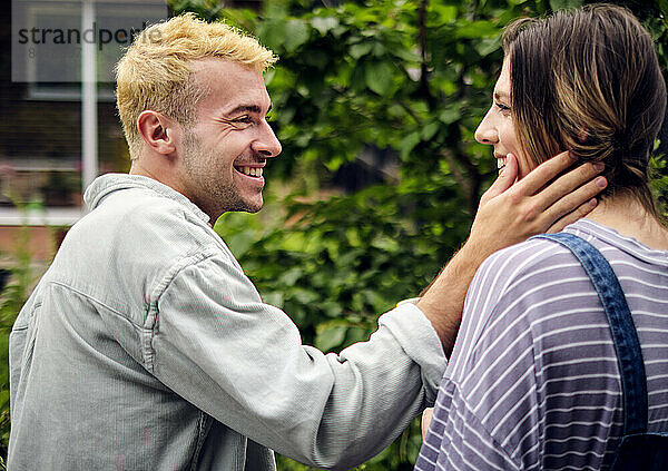 Happy boyfriend touching cheek of girlfriend in back yard