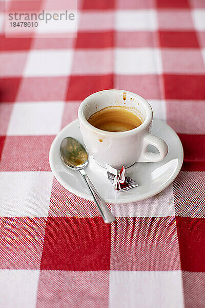 Leere Kaffeetasse liegt auf einer rot karierten Tischdecke