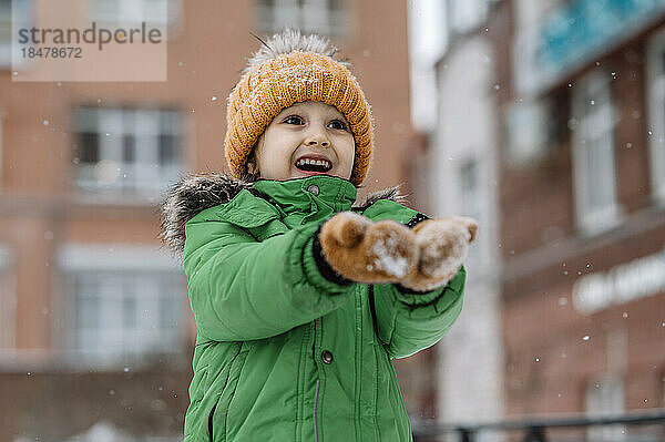 Netter Junge genießt den Schneefall im Winter