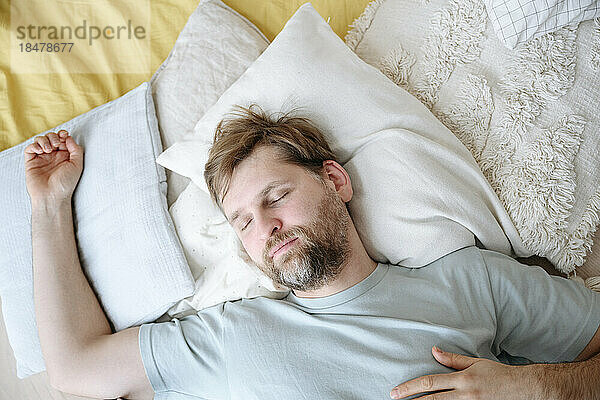 Man sleeping on cushions at home