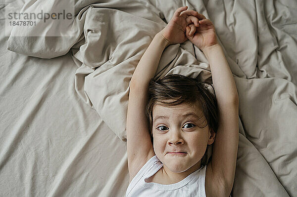 Verspielter Junge  der sich zu Hause auf dem Bett ausdehnt