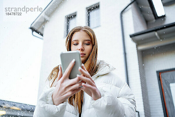 Teenager-Mädchen benutzt Smartphone außerhalb des Hauses