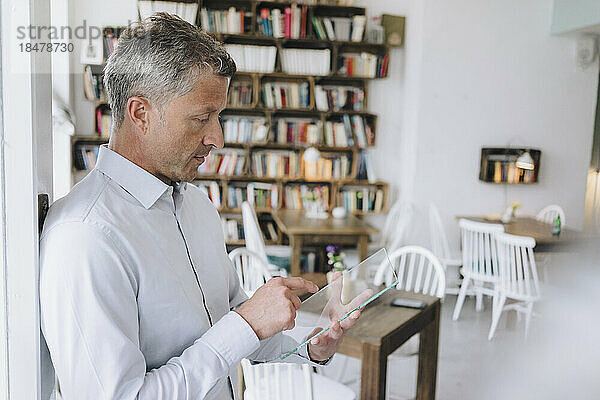Businessman using futuristic transparent tablet PC in cafe