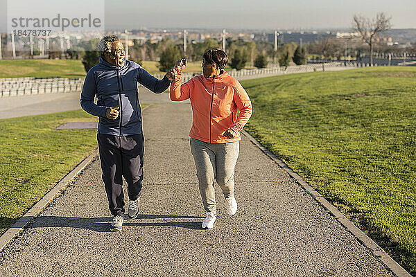 Glückliches älteres Paar joggt auf Fußweg im Park