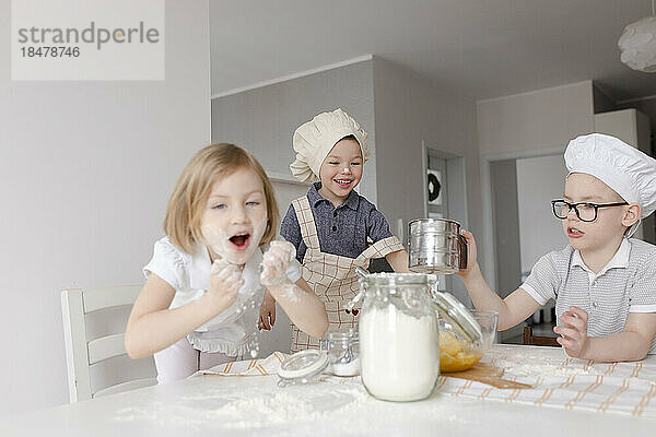 Children having fun preparing dough with flour at home