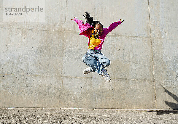 Frau tanzt an einem sonnigen Tag vor einer Mauer Breakdance