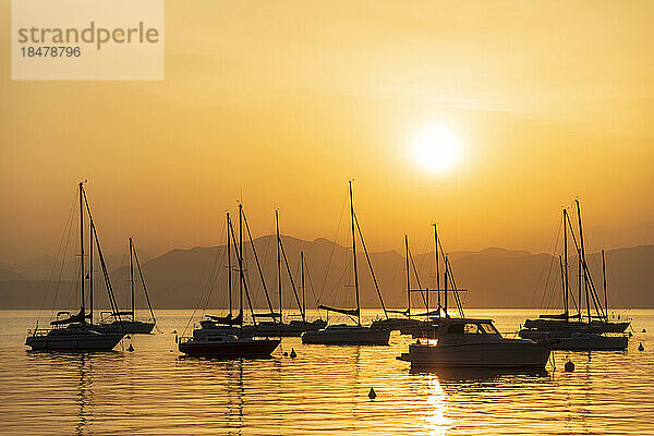 Italien  Venetien  Bardolino  Silhouetten von Segelbooten  die bei Sonnenuntergang im Gardasee schwimmen