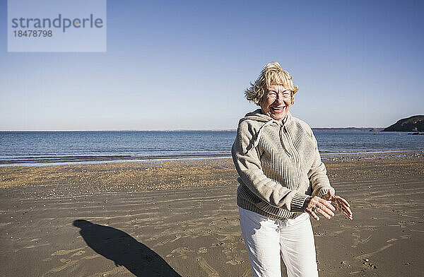 Sorglose Seniorin tanzt und hat Spaß am Strand