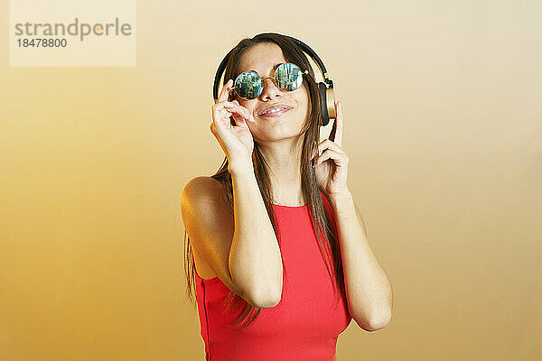 Lächelnde Frau mit Steampunk-Sonnenbrille und Musikhören über Kopfhörer